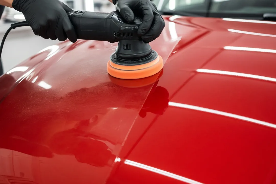 Dual-action polisher correcting the paint on a red hood