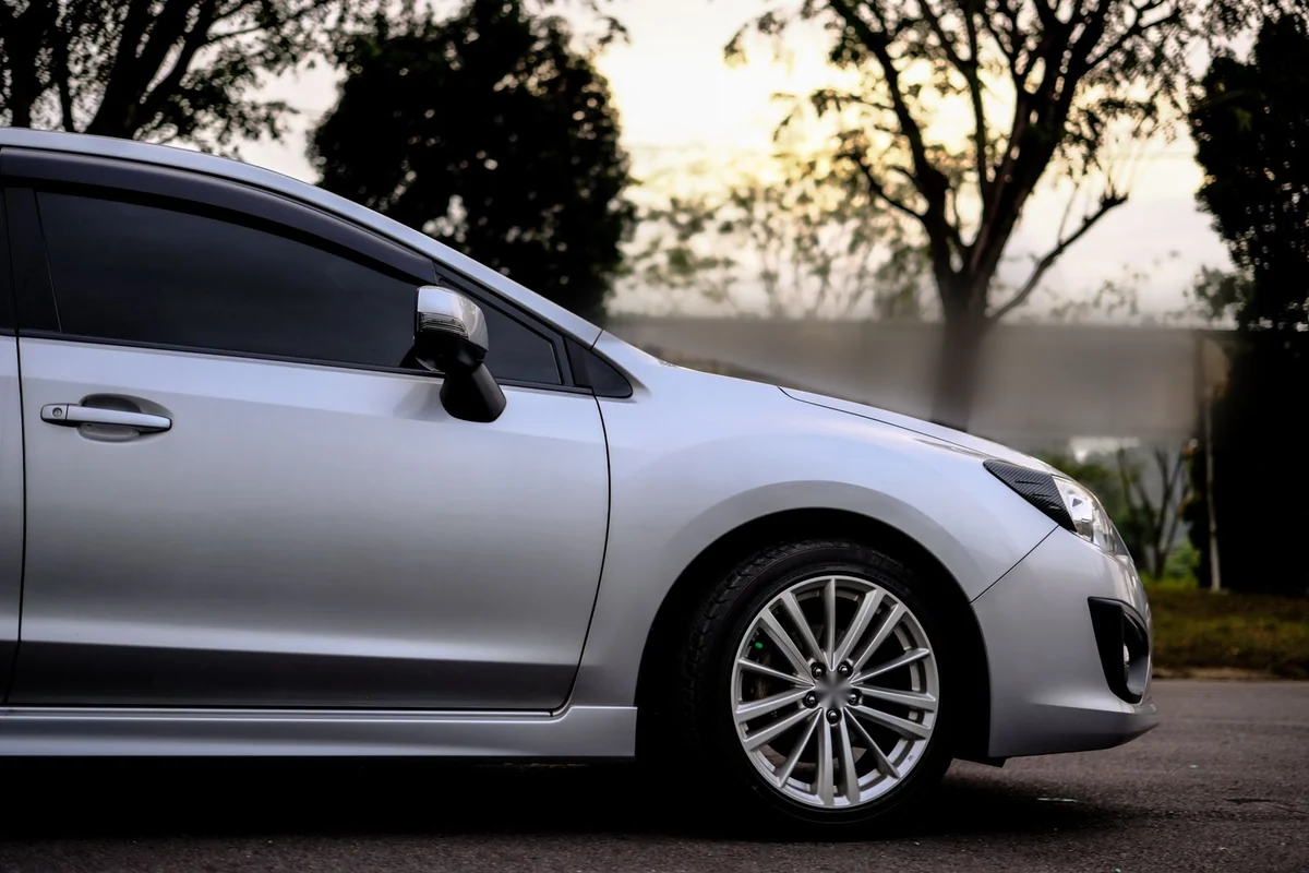Silver hatchback with tinted side windows parked on a quiet road at dusk